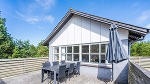 A modern house with a deck, large windows, and outdoor furniture. - 4 Person Holiday Home in Blavand (Blavand)
