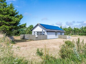 A single-story house with a sloped roof, a fenced yard, and a clear sky. - 4 Person Holiday Home in Blavand (Blavand)