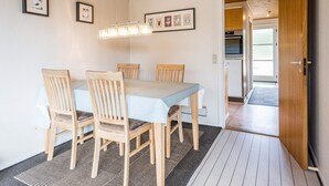 A dining area with a wooden table and chairs, a ceiling light fixture, and framed pictures on the wall. - 4 Person Holiday Home in Blavand (Blavand)