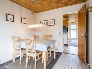 A dining area with a wooden table and chairs, a ceiling light fixture, and framed pictures on the wall. - 4 Person Holiday Home in Blavand (Blavand)