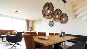A modern dining area with a wooden table, brown upholstered chairs, and pendant lights.
