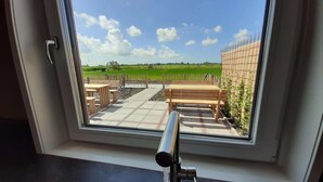 A kitchen with a window view of a patio area with outdoor seating and a metal fence.