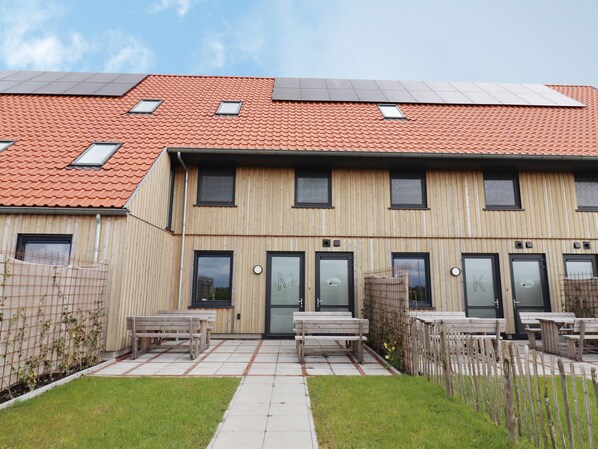 A modern multi-story building with a red-tiled roof, wooden facade, and multiple windows. - Lovely Villa on the Frisian Water (Leons)