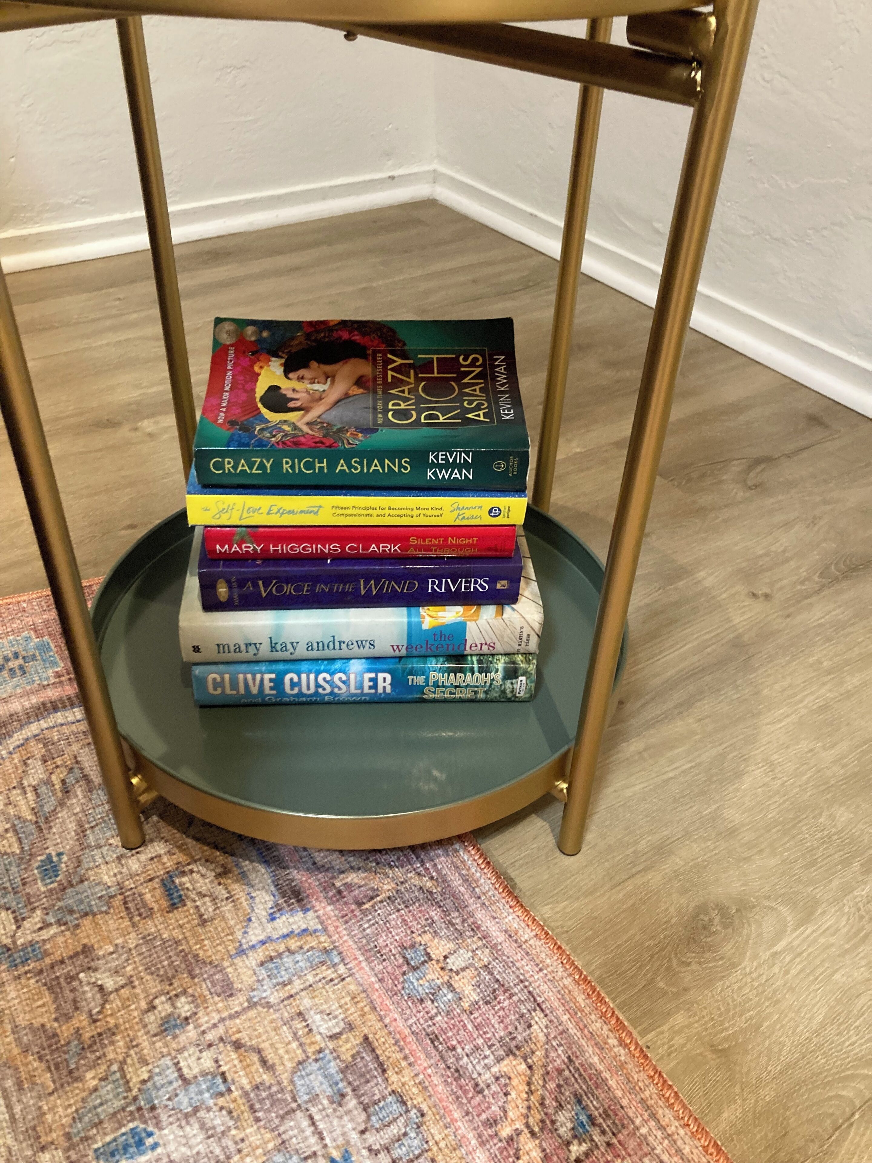 Une pile de livres sur une table en verre dont le cadre est doré.