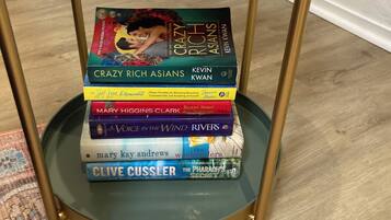 Une pile de livres sur une table en verre dont le cadre est doré.