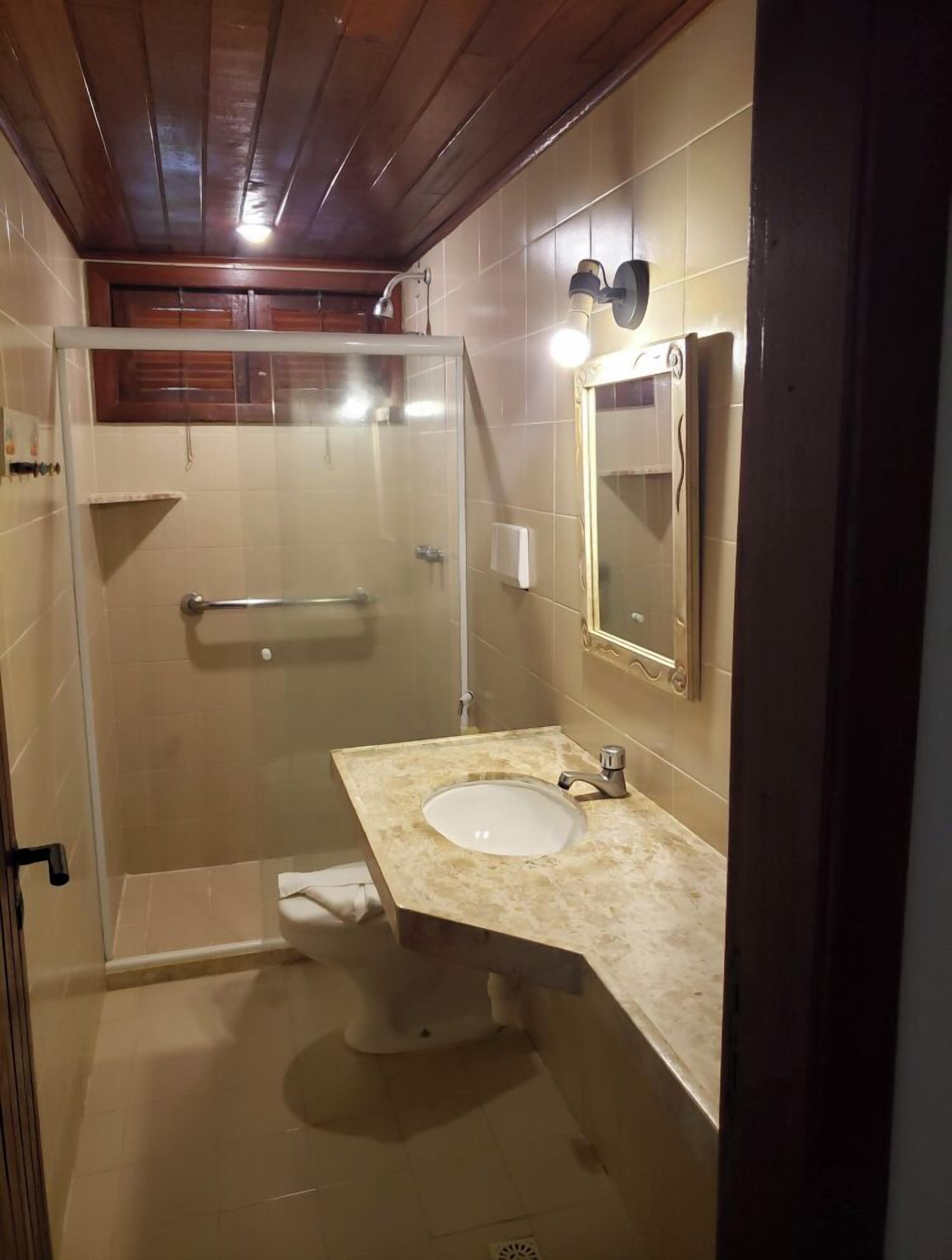 A bathroom with a glass-enclosed shower, a sink with a mirror, and a toilet.