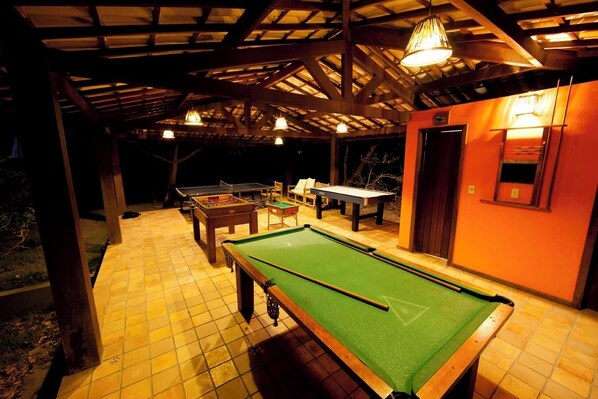Zona de piscina al aire libre con mesa de fútbol de mesa, mesa de billar y mesa de tenis de mesa.