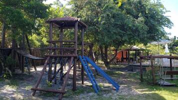 A playground with a wooden climbing structure and a slide.