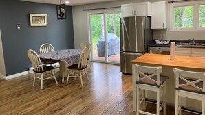 Una cucina moderna con mobili bianchi, un frigorifero in acciaio inossidabile e un tavolo da pranzo in legno con sedie.