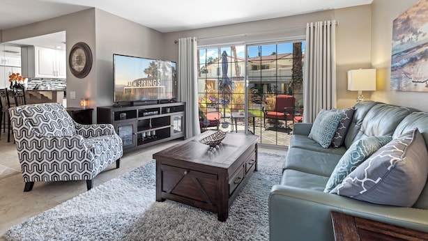 Ein modernes Wohnzimmer mit Sofa, Sessel, Couchtisch und Fernseher.