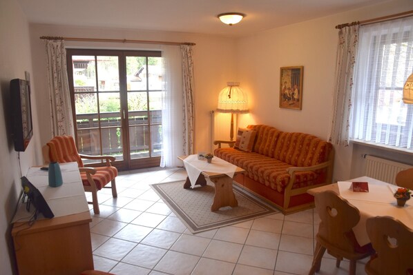 A living room with a sofa, a coffee table, a lamp, and a television.