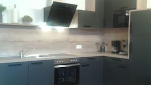 A modern kitchen with grey cabinets, a stainless steel oven, and a microwave. - Holiday Apartment Tulpe Schuniglhof (Neukirchen Beim Heiligen Blut)