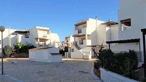 A residential area with white buildings, a paved courtyard, and a small white structure in the center.