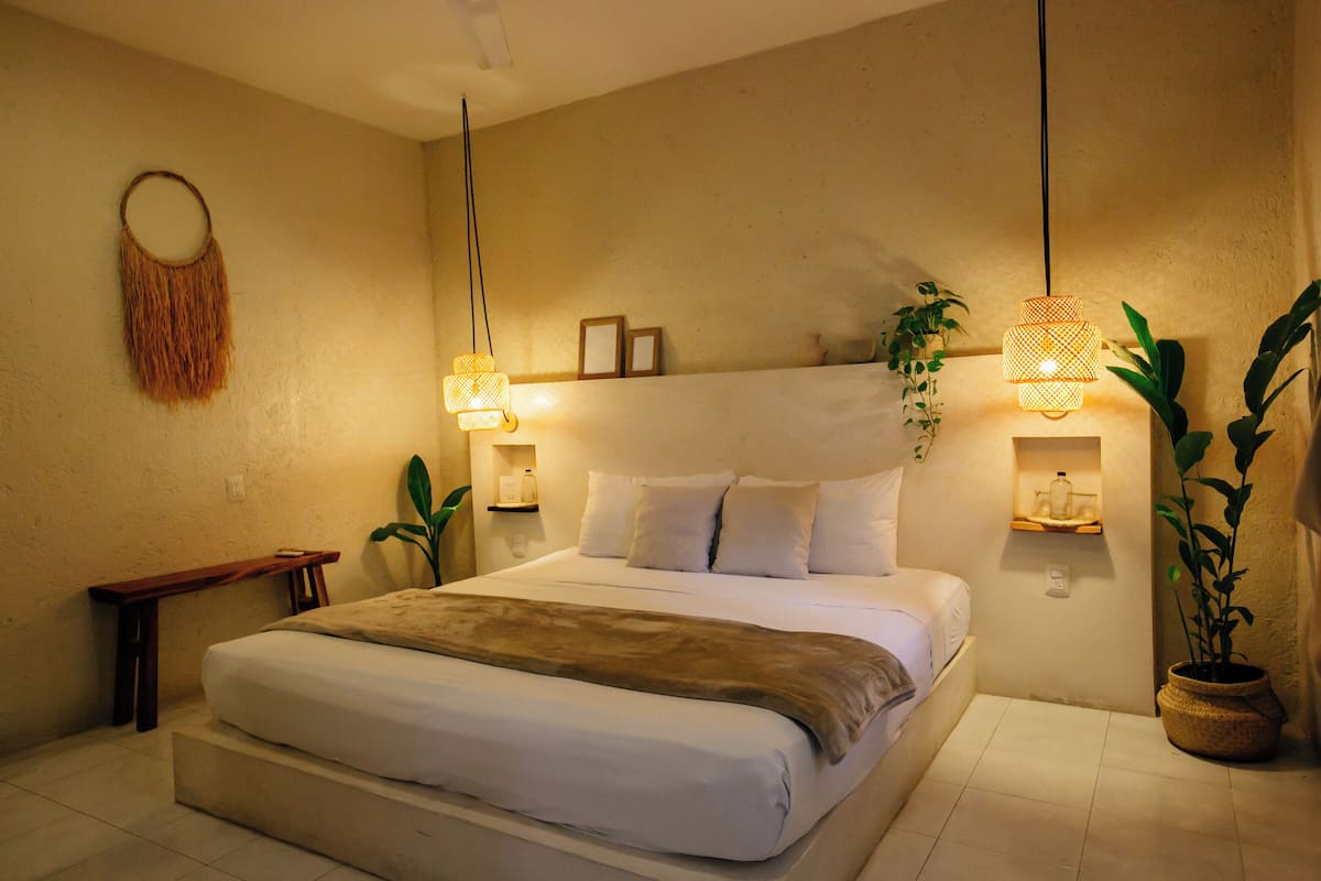 A neatly arranged bedroom with a large bed, bedside tables, and hanging lamps.