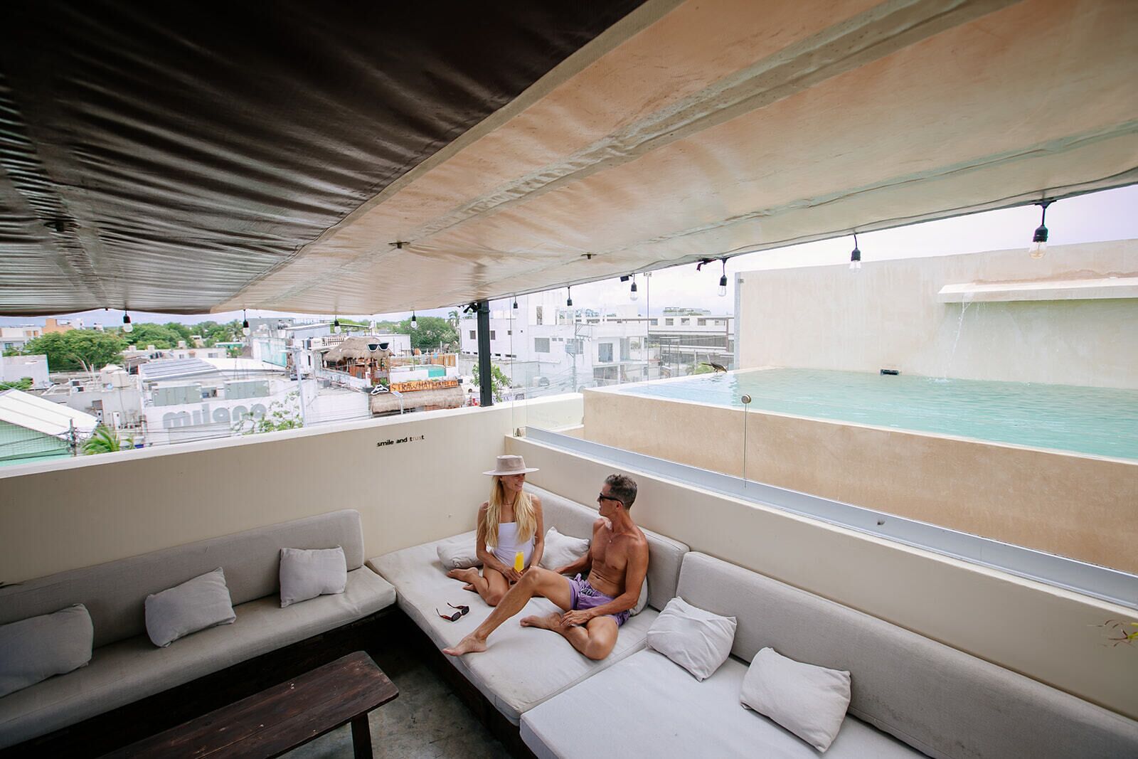A rooftop lounge with a pool, seating area, and city views.