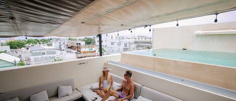 A rooftop lounge with a pool, seating area, and city views.