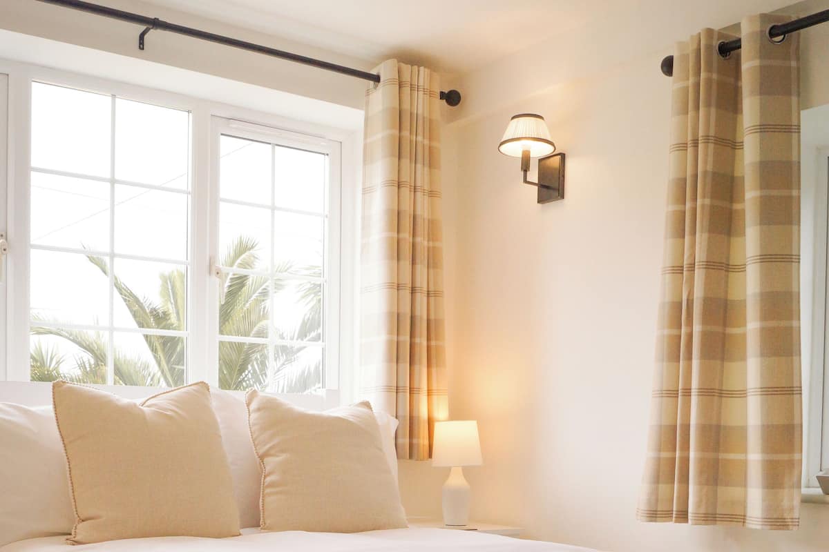 A bedroom with a large bed, a nightstand, a lamp, and curtains.