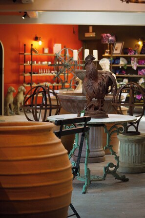 A rustic interior with a wrought iron table and chairs, surrounded by terracotta pots and a decorative rooster statue. - Lemon Tree (Dorchester)