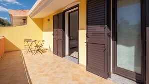 Ein Balkon mit Tisch und Stühlen, einer Schiebetür und Blick zum Himmel.