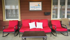 Espaço ao ar livre do North Beach Hotel com um sofá e cadeiras vermelhas, uma pequena mesa e um letreiro emoldurado acima.