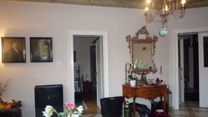 A room with a chandelier, a mirror, a dresser, and a small table with a vase of flowers. - Nice Apartment in Radebeul (Radebeul)