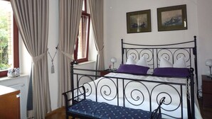 A bedroom with a metal bed frame, a window with curtains, and two framed pictures on the wall. - Nice Apartment in Radebeul (Radebeul)