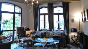 A spacious living room with a large sofa, a coffee table, and a chandelier. - Nice Apartment in Radebeul (Radebeul)