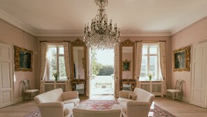 A spacious room with a large chandelier, four white armchairs, and a patterned rug. - Agerup Comfortable Holiday Residence (Sakskobing)
