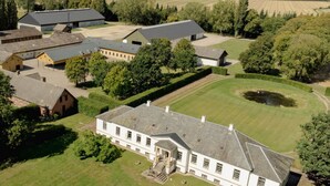 An aerial view of a large estate with multiple buildings, including a prominent white house with a symmetrical facade and a central entrance. - Agerup Comfortable Holiday Residence (Sakskobing)