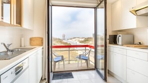 A modern kitchen with a glass door leading to a balcony with a view of the beach. - Apartment Near Dunes in Koksijde (Koksijde)