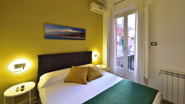 Une chambre d’hôtel avec un lit, un tableau, une table de chevet et une fenêtre avec des rideaux.