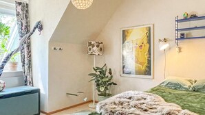 A bedroom with a bed, a desk, a lamp, a framed picture, and a window with curtains. - 4 Star Holiday Home in Vastervik (Vastervik)