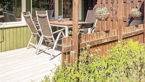 Une terrasse extérieure avec une plateforme en bois, une table et des chaises, ainsi que des jardinières suspendues.