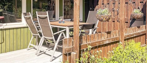 An outdoor patio with a wooden deck, a table with chairs, and hanging planters.