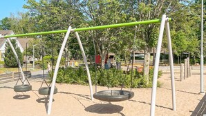 A playground with swings and tire swings, surrounded by sand and trees. - 4 Star Holiday Home in Vastervik (Vastervik)