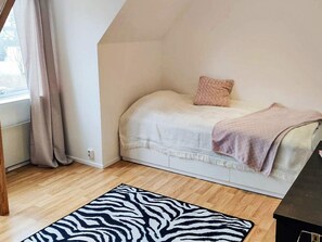 A bedroom with a bed, a window with curtains, a zebra-patterned rug, and a wooden floor. - 4 Star Holiday Home in Vastervik (Vastervik)