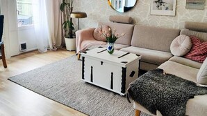 A living room with a sofa, a coffee table, a potted plant, a mirror, and artwork on the wall. - 4 Star Holiday Home in Vastervik (Vastervik)