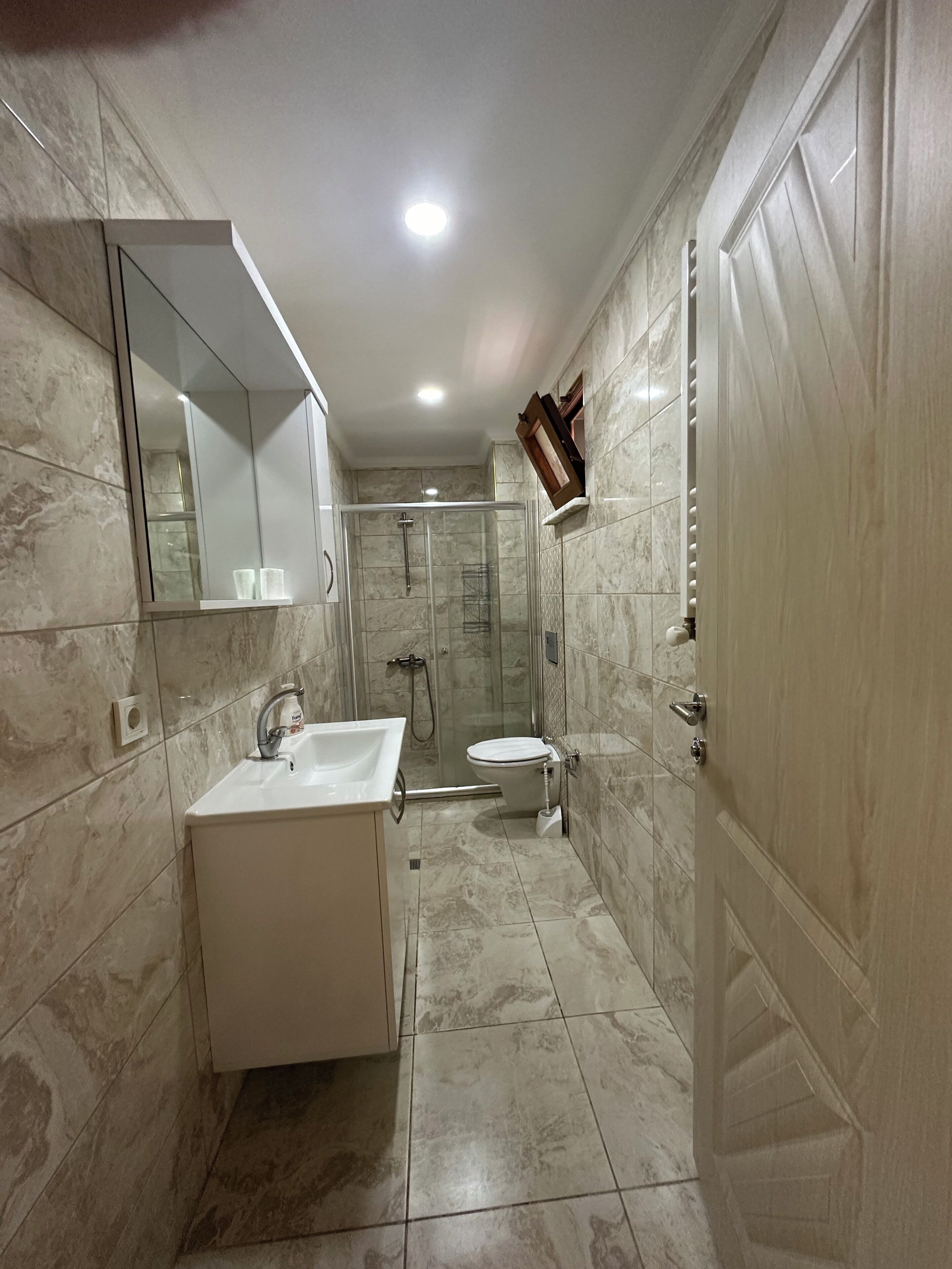 A bathroom with a glass-enclosed shower, a white sink, and a toilet.