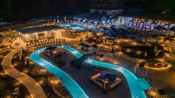A well-lit outdoor swimming pool area with lounge chairs and a covered seating area. - Luxury Chalet | Indoor pool | Hot Tub | Game Room (Sevierville)