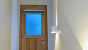 A wooden door with a window, a light switch on the wall, and a tiled staircase.