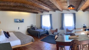 A cozy, rustic room with a bed, two sofas, a dining table, and a kitchen area.