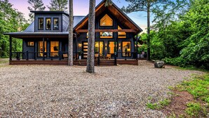 Een chalet met een veranda, grote ramen en een stenen fundering.