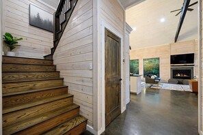 A wooden staircase leading to a living area with a fireplace and a television.