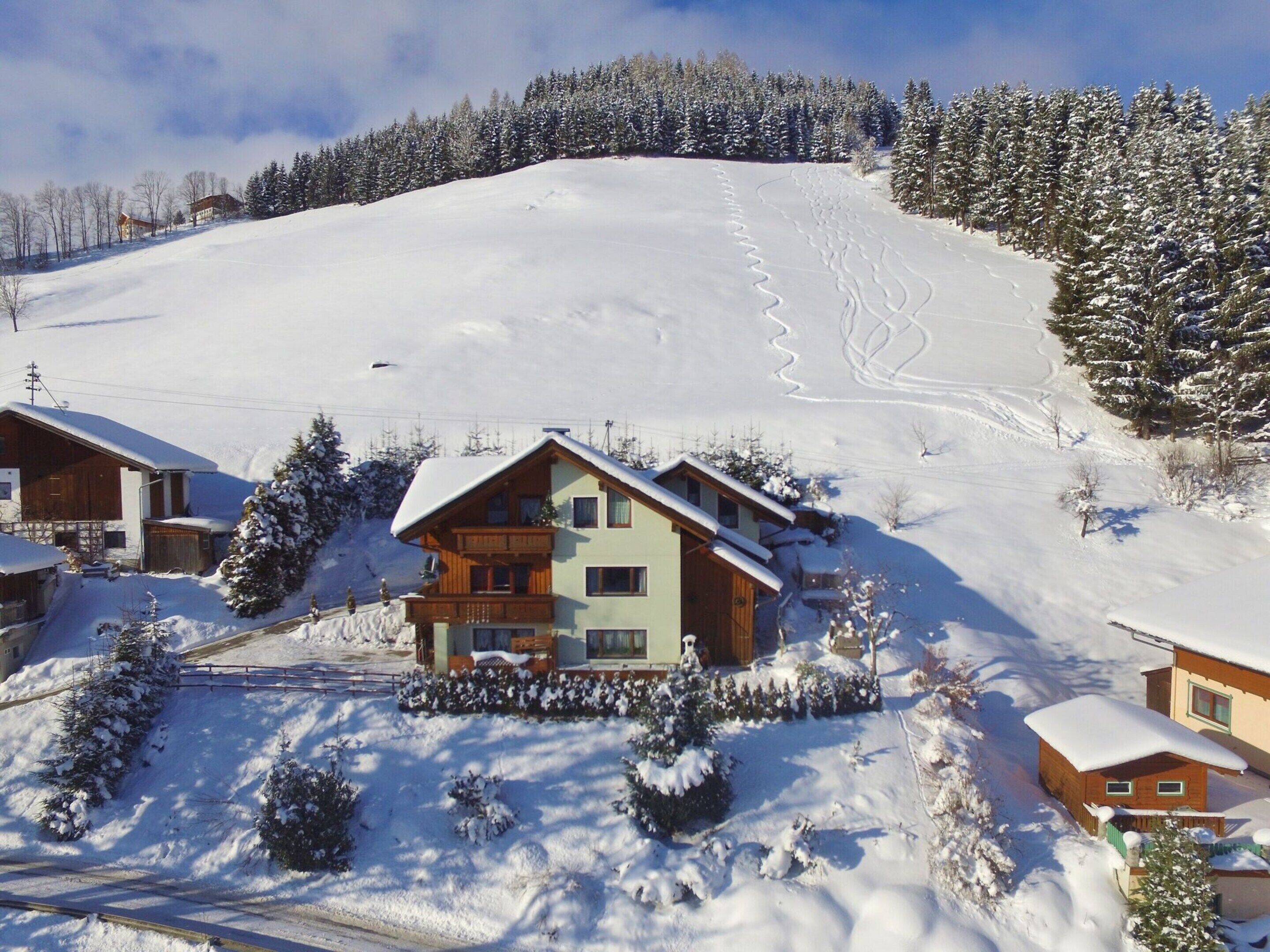 A snow-covered mountain with a ski slope and a wooden chalet with a balcony.