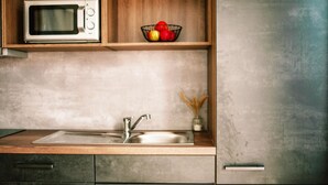 A kitchen with a microwave, sink, and wooden shelves. - Apartment in Hohentauern With Sauna (Hohentauern)