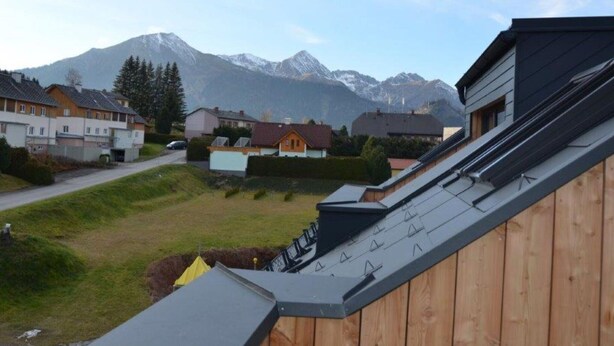 A residential area with houses, a wooden deck, and a mountain backdrop. - Apartment in Hohentauern With Sauna (Hohentauern)