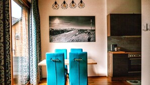 A dining area with a table and four chairs, a kitchen with cabinets and appliances, and a large framed picture on the wall. - Apartment in Hohentauern With Sauna (Hohentauern)