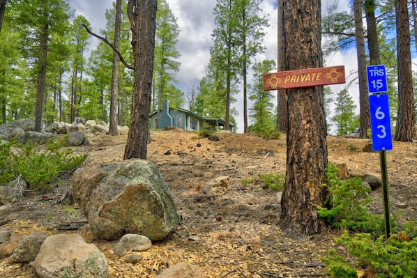 A rustic cabin in a forested area with a private sign and a trail marker.