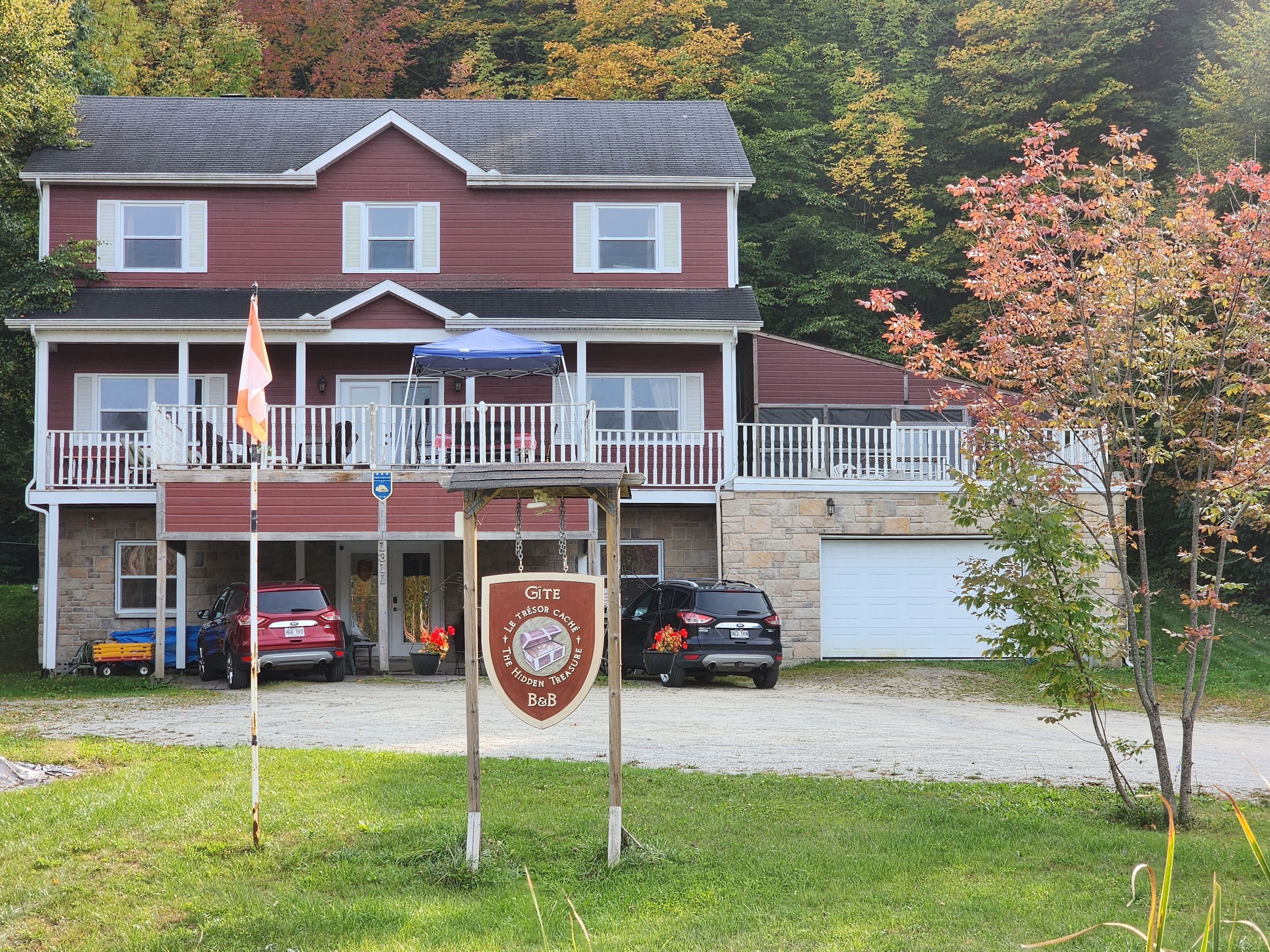 Una casa de dos pisos con balcón, garaje y un letrero que dice 'Gîte Le Trésor Caché B&B'.