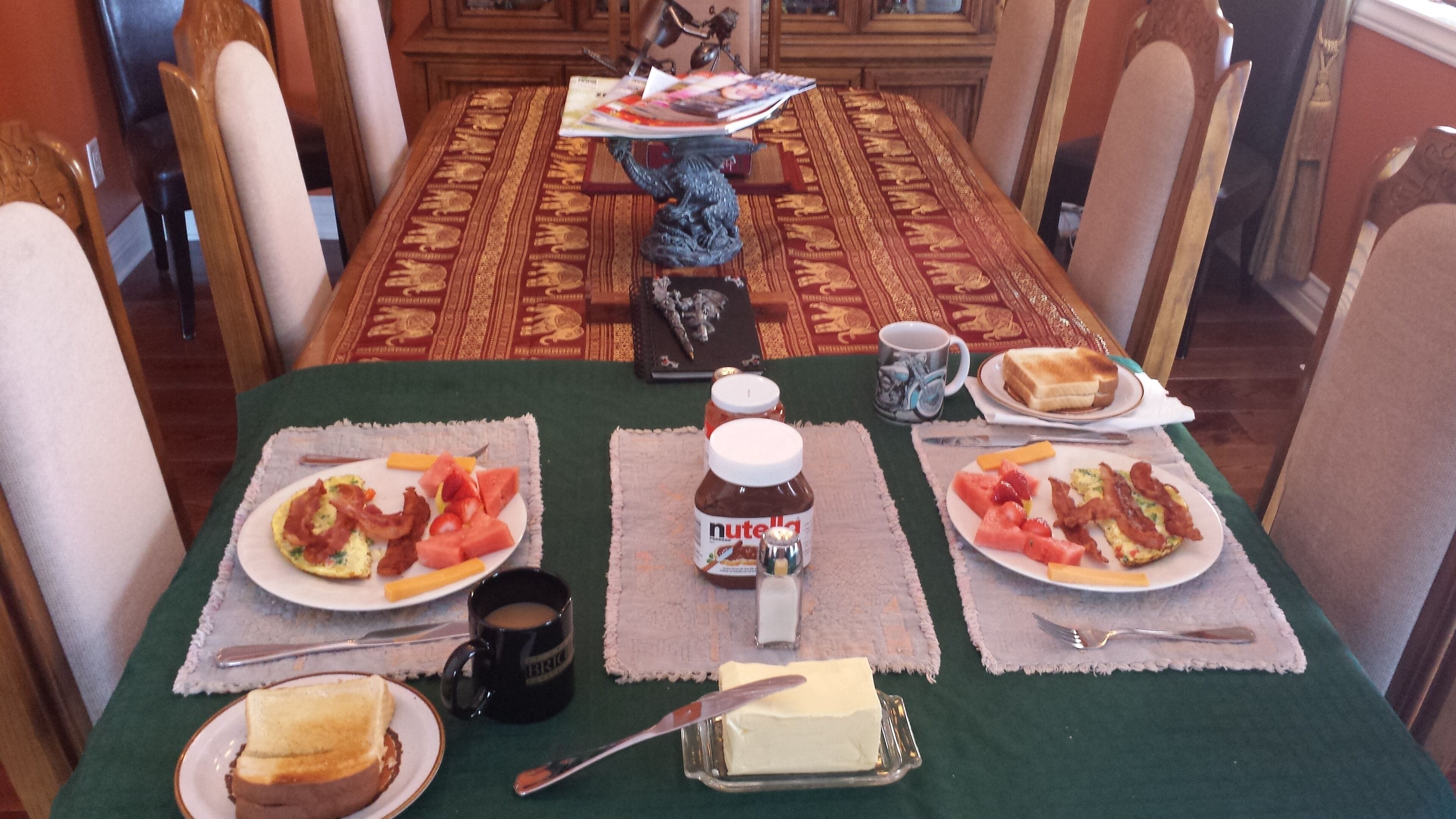 A dining table set with breakfast items including toast, eggs, bacon, and jam.